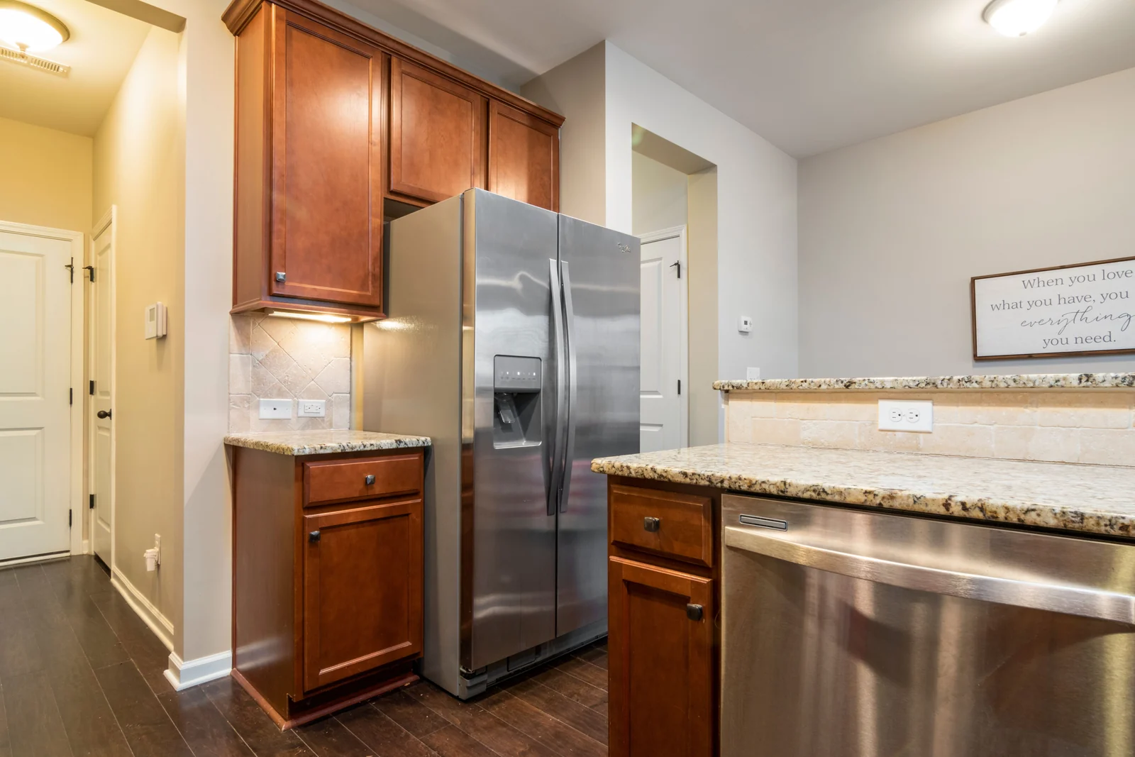 Cherry cabinets with a granite worktop beside a tall fridge